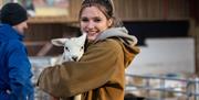 A female farm worker holding a lamb at the Court Farm Country Park in Weston-super-Mare