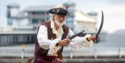 A pirate with a sword and gun outside The Grand Pier at the Weston-super-Mare Sea Shanty Festival