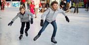 Two boys in grey jackets ice skating