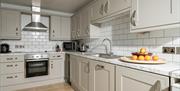 A modern kitchen with white units and tiles in a self catering cottage at Webbington Farm, near Weston-super-Mare