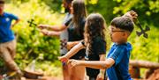 A group of four people, including a young boy in the foreground wearing glasses taking part in the axe throwing activity at the Mendip Activity Centre