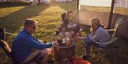 A family cooking their meal outdoors while sitting on deckchairs at the Mendip Basecamp, near Weston-super-Mare