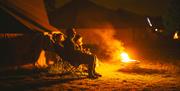 A family in deckchairs sitting in the nigh time glow of a campfire at the Mendip Family Festival