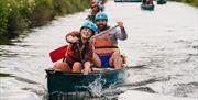 A girl and a man leading a procession of canoes on the river at the Mendip Activity Centre, near Weston-super-Mare