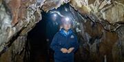 A girl with a helmet and head torch walking through a cave at the Mendip Activity Centre