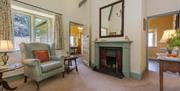 Light airy, high-ceiling living room with open fireplace, green armchair, large mirror and period furniture