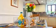 A large vase of flowers adorn a set breakfast table in a kitchen dining room at Norton Court Farm self-catering cottages, Sand Bay near Weston-super-M