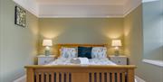 A green and white painted bedroom featuring a large wooden double bed with matching towels and linen at Norton Court Farm Holiday Cottages, Sand Bay n