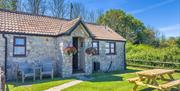 Exterior view of a single storey barn conversion self-catering bungalow at Norton Court Farm, Sand Bay, near Weston-super-Mare  with hanging baskets o