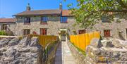 Exterior image of a fenced path leading towards the stone buildings of Norton Court Farm self-catering holiday cottages near Weston-super-Mare