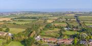 An aerial view of the Norton Court Farm self-catering holiday cottages showing the surrounding patchwork of fields leading to the sea at Sand Bay, nea