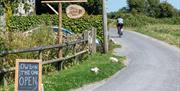 A cyclist rides past a blackboard sign advertising a cafe