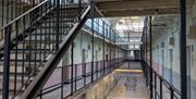 Inside of a prison wing with a metal staircase in the foreground