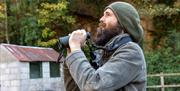 A bearded birdwatcher with his binoculars at the Old Town Quarry, Weston-super-Mare