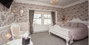 Interior of a luxury hotel double bedroom with white furniture and flowery wallpaper