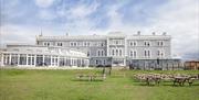 View to a palatial large hotel with a large lawn in the foreground