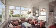 A bright airy hotel seating area with leather armchairs and sofas