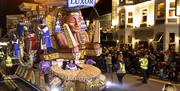 A massive Egyptian-themed huge brightly-coloured carnival float which is as tall as the buildings it is passing.