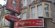 Image of the outside of The Regency pub with a pub sign and red sign