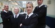 Four prison guards standing in the middle of a prison wing