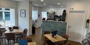 Wooden tables with chairs around them inside the empty Sand Bay Fish and Chip Shop.