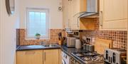 Kitchen inside the Seaside Apartments Weston-super-Mare featuring wooden units, appliances, tiles and a dark worktop