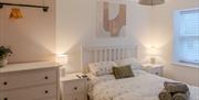 Cream-coloured double bedroom at the Seaside Apartments, Weston-super-Mare. The bed is made up and has towels, pillows and cushions neatly on top. The