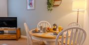 The living room diner at the Seaside Apartments, Weston-super-Mare. The room features a round dining table with four white chairs, pictures and a plan