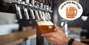 A hand tilting a glass and filling it with beer at the pump