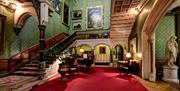 Large grand room with sweeping staircase in an historic house with statue and chandelier