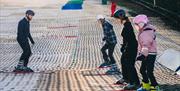 Family of three (two kids and adults) on Mendip Activity Centre's dry slope, learning to ski with instructor.