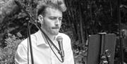 black and white picture of the artist at a keyboard in woodlands