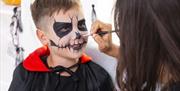 A face painter painting a Halloween face on a boy