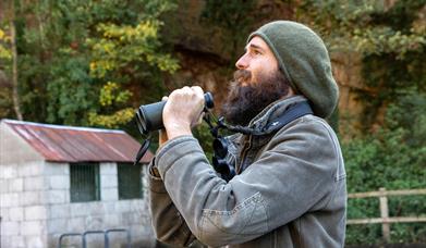A bearded birdwatcher with his binoculars at the Old Town Quarry, Weston-super-Mare