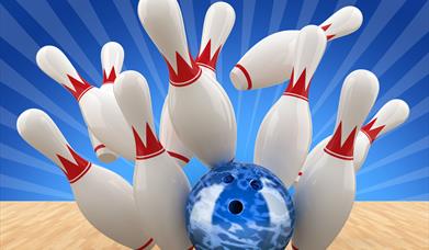 A blue bowling ball sending the pins flying at the end of a wooden bowling alley