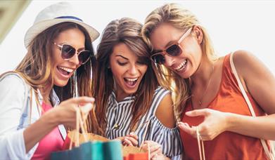 Three women looking excitedly at their shopping bags