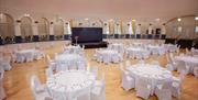Interior of a circular ballroom set out with tables dressed in white for a wedding