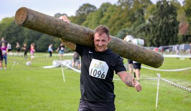 Competitor carrying a large log on his shoulders