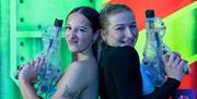 Two women standing back to back holding toy guns at an adult soft play party night