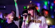 A long haired man in a cowboy hat singing karaoke into a microphone