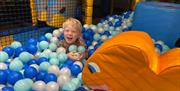 Child laughing in ball pond with white and blue plastic balls