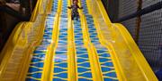 Yellow and blue great big slide with child sliding from top