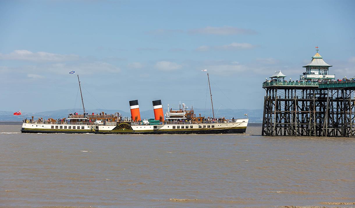 A paddle steamer passing by the end of a pier