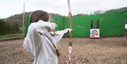 Child firing an arrow at an archery target