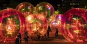 People stood next to lit up inflatable balls