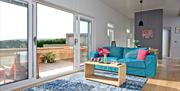Sitting room with patio doors open to the deck with plants and sunlounger