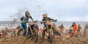 A motorbike rider has to get off his bike during a beach race as he tries to get his machine over a sand obstacle