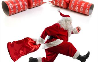 Santa Claus with a red sack running beneath a Christmas cracker