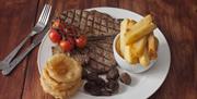 Steak dinner with mushrooms, chips, tomatoes and onion rings