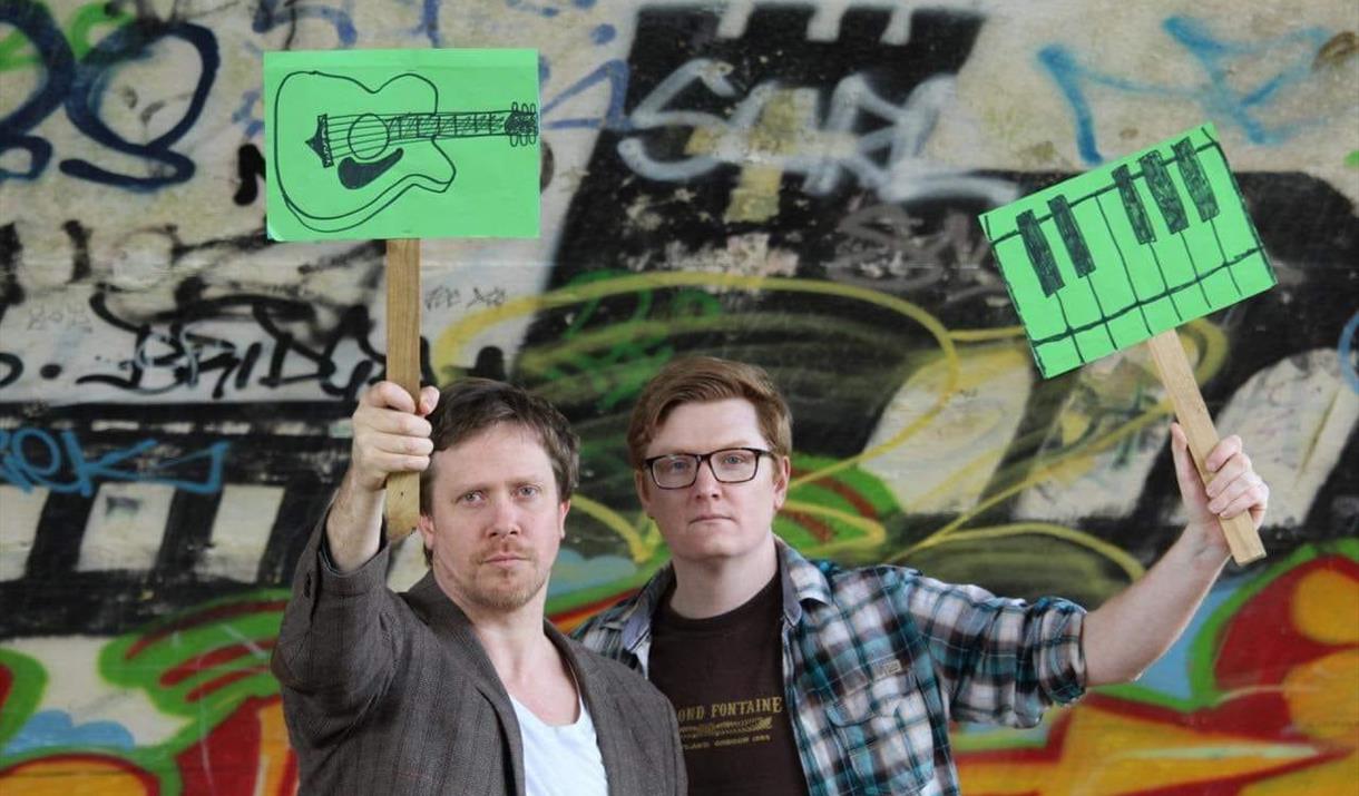 Gavin and John - musicians - holding up green musical placards